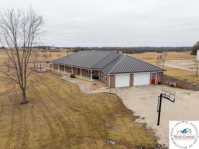 country-style home with a porch, metal roof, brick siding, concrete driveway, and an attached garage