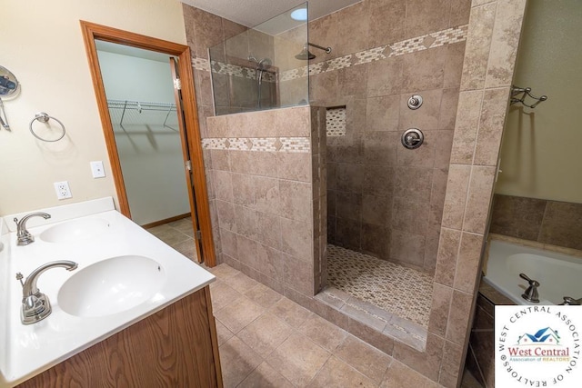 full bathroom with a walk in closet, a garden tub, a sink, and a walk in shower