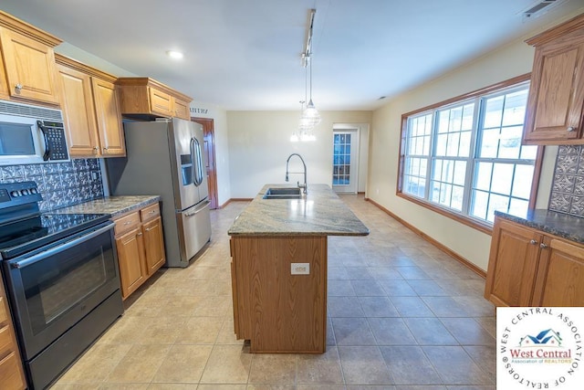 kitchen with tasteful backsplash, a kitchen island with sink, stainless steel fridge, a sink, and black electric range oven