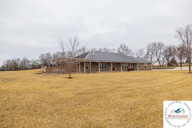back of house with a lawn, a standing seam roof, metal roof, and brick siding