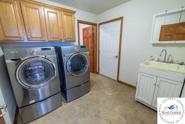 washroom featuring cabinet space, a sink, independent washer and dryer, and baseboards