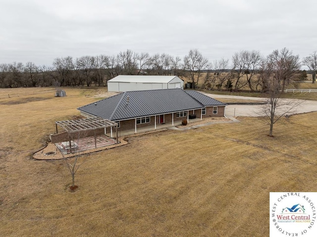 back of house with metal roof and a lawn