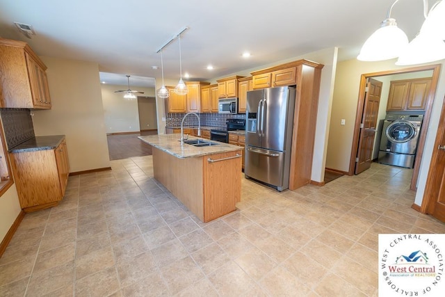 kitchen with a sink, baseboards, stainless steel appliances, and washer / clothes dryer