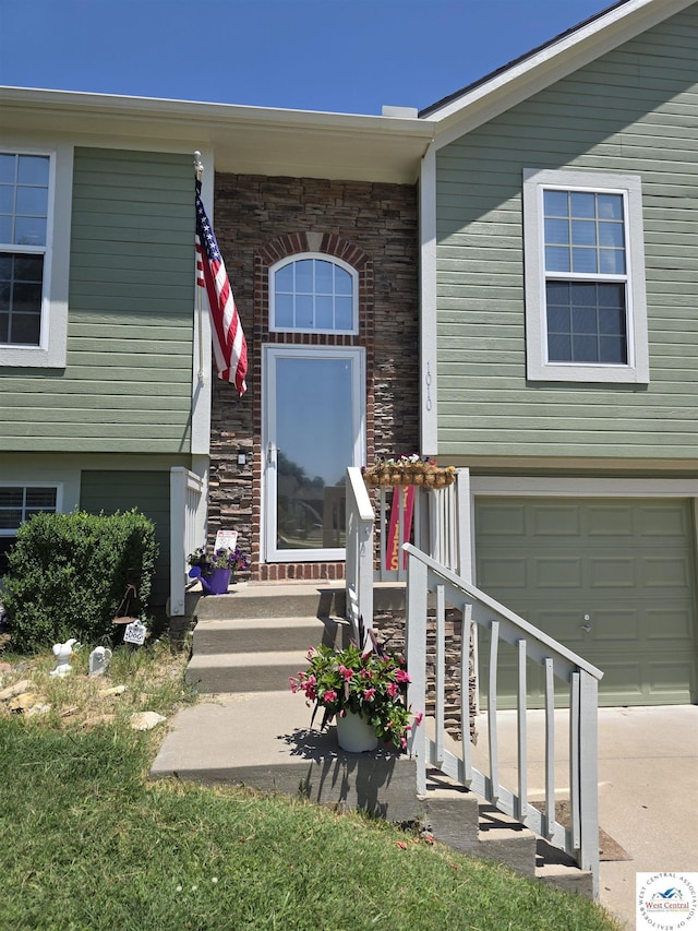 1010 NW Scenic Dr, Grain Valley, MO 64029 - doorway to property featuring a garage, driveway, and stone siding