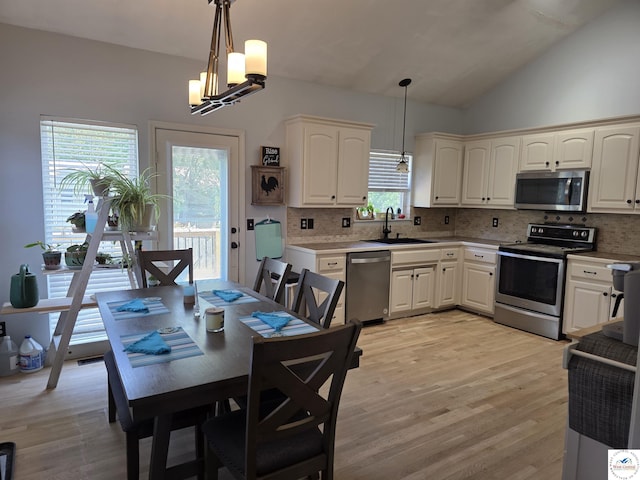 1010 NW Scenic Dr, Grain Valley, MO 64029 - kitchen featuring stainless steel appliances, backsplash, a chandelier, light wood finished floors, and vaulted ceiling