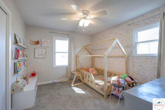 carpeted bedroom featuring a ceiling fan, baseboards, wallpapered walls, and multiple windows