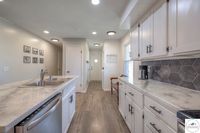 kitchen featuring white cabinetry, stainless steel appliances, decorative backsplash, and a sink
