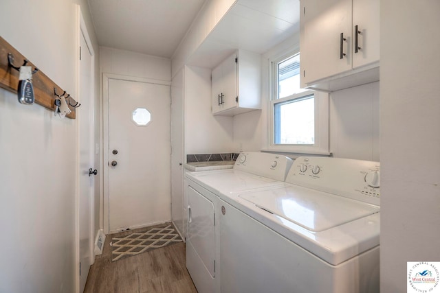 clothes washing area featuring dark wood-style flooring, washer and dryer, and cabinet space