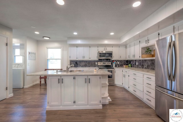 kitchen featuring white cabinetry, open shelves, a sink, appliances with stainless steel finishes, and washer / dryer