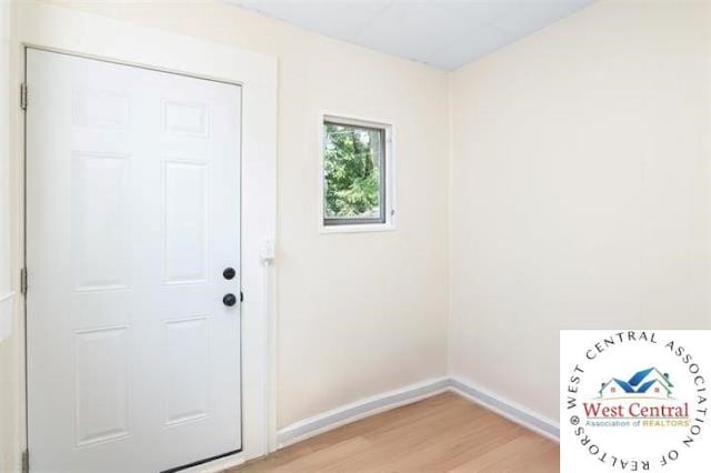 doorway to outside featuring baseboards and light wood-type flooring