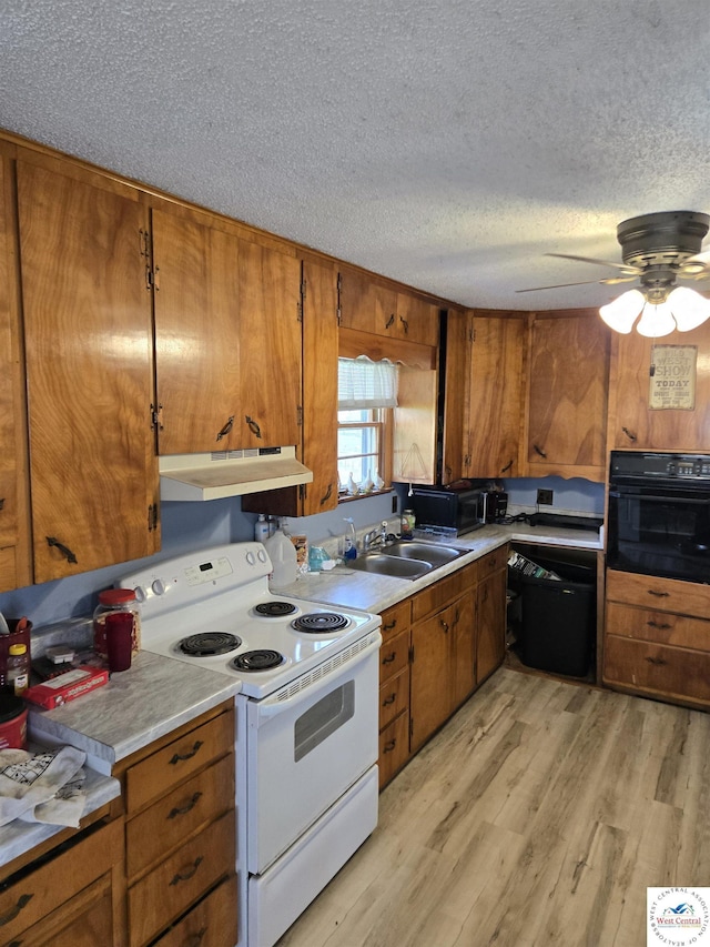 kitchen with light countertops, under cabinet range hood, black appliances, and brown cabinets