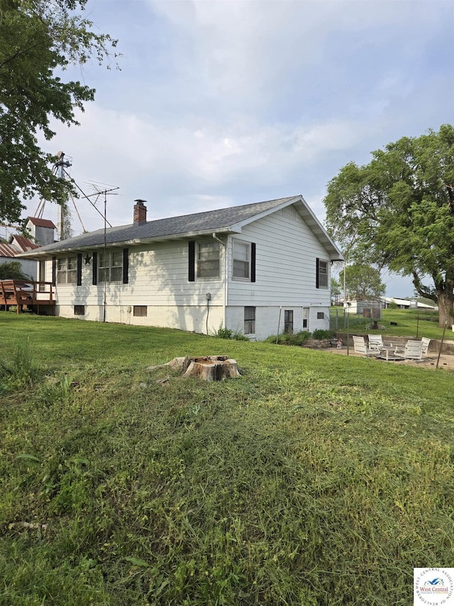 rear view of property with a yard, a chimney, and roof with shingles