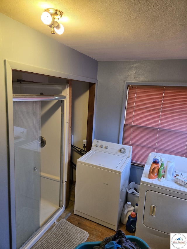 washroom with washing machine and clothes dryer, a textured ceiling, laundry area, and wood finished floors