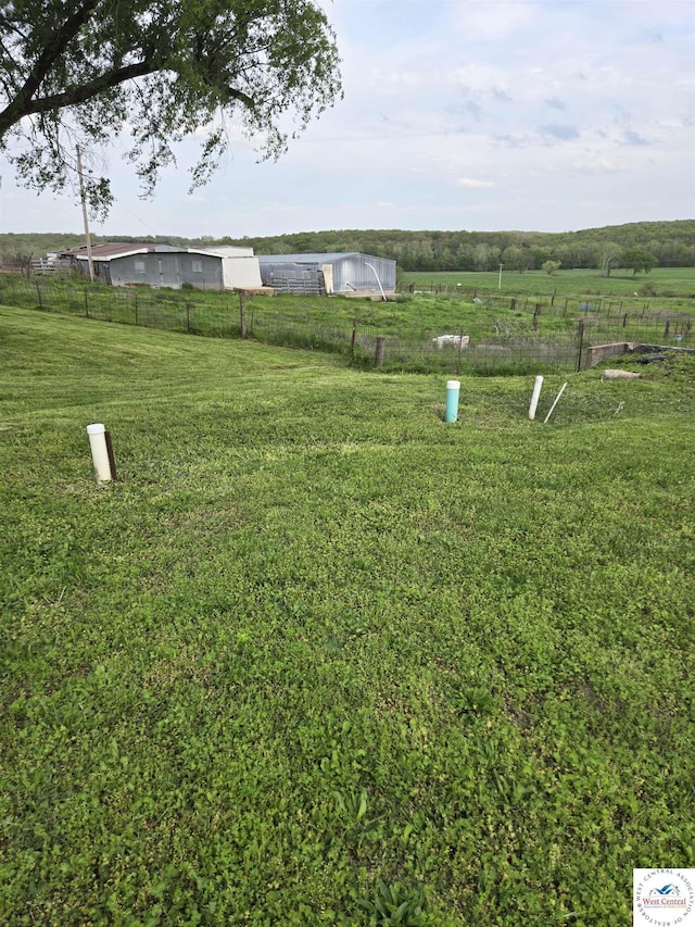 view of yard featuring a rural view, fence, an outbuilding, and an outdoor structure