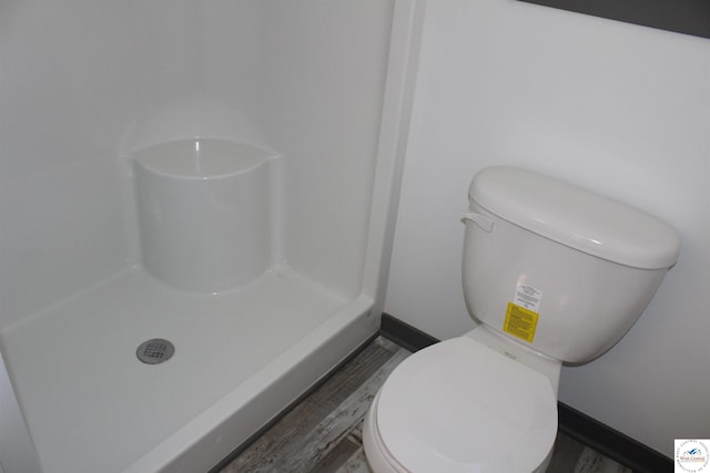 bathroom featuring a shower, wood finished floors, toilet, and baseboards