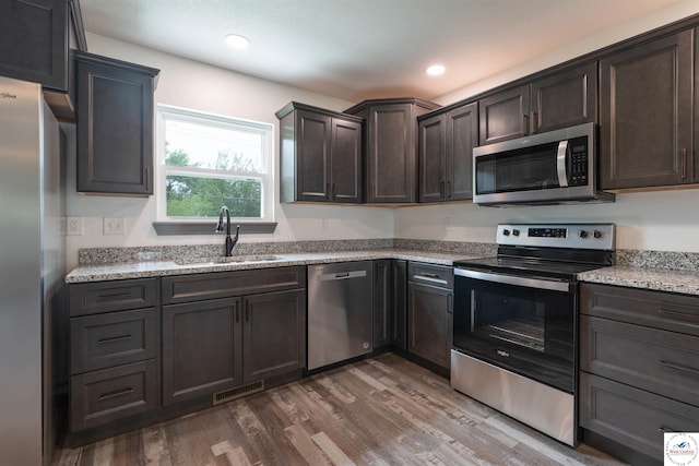704 E 16th St, Sedalia, MO 65301 - kitchen with stainless steel appliances, a sink, wood finished floors, dark brown cabinetry, and recessed lighting