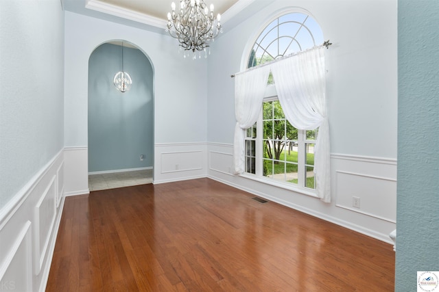 3375 Cedar St, Sedalia, MO 65301 - empty room featuring a chandelier, arched walkways, ornamental molding, a wainscoted wall, and a raised ceiling