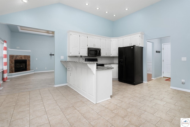 3375 Cedar St, Sedalia, MO 65301 - kitchen featuring black appliances, high vaulted ceiling, a peninsula, light stone countertops, and white cabinetry