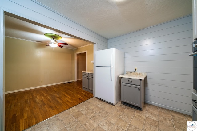 1315 Maple Ln, Sedalia, MO 65301 - kitchen featuring wooden walls, gray cabinetry, a ceiling fan, and freestanding refrigerator