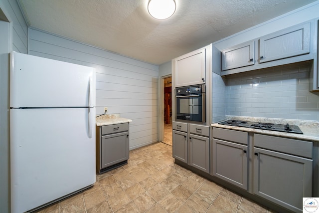 1315 Maple Ln, Sedalia, MO 65301 - kitchen featuring tasteful backsplash, light countertops, black appliances, wooden walls, and gray cabinets