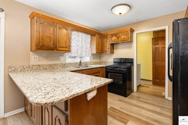 5900 Apple Rd, Sedalia, MO 65301 - kitchen featuring brown cabinets, a sink, light wood-style floors, black appliances, and a peninsula