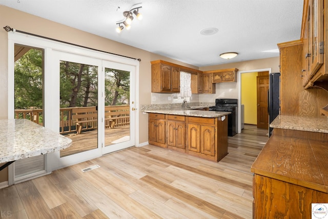 5900 Apple Rd, Sedalia, MO 65301 - kitchen featuring black appliances, a peninsula, light wood-type flooring, and brown cabinetry