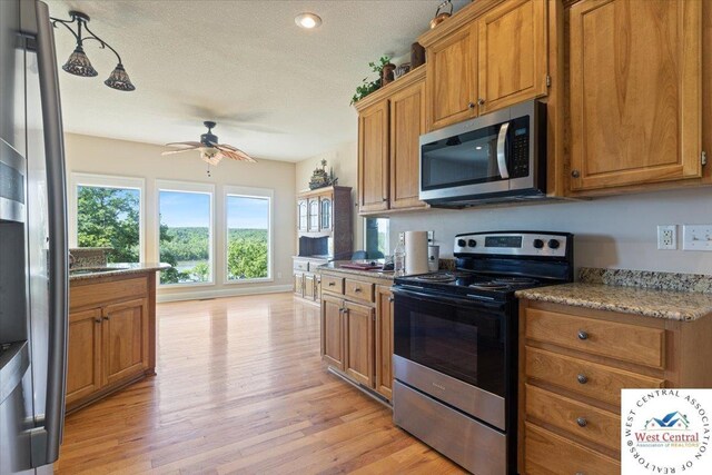 22714 Lake Dr, Warsaw, MO 65355 - kitchen with appliances with stainless steel finishes, brown cabinets, ceiling fan, light wood-style floors, and a textured ceiling