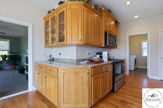 22714 Lake Dr, Warsaw, MO 65355 - kitchen with range, stainless steel microwave, light wood-style flooring, glass insert cabinets, and light stone counters