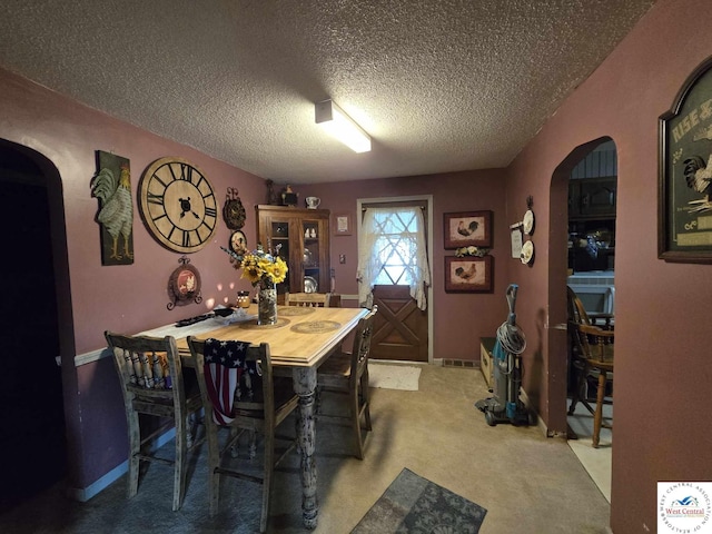 512 N Price Ln, Clinton, MO 64735 - dining area featuring arched walkways, light colored carpet, baseboards, visible vents, and a textured ceiling