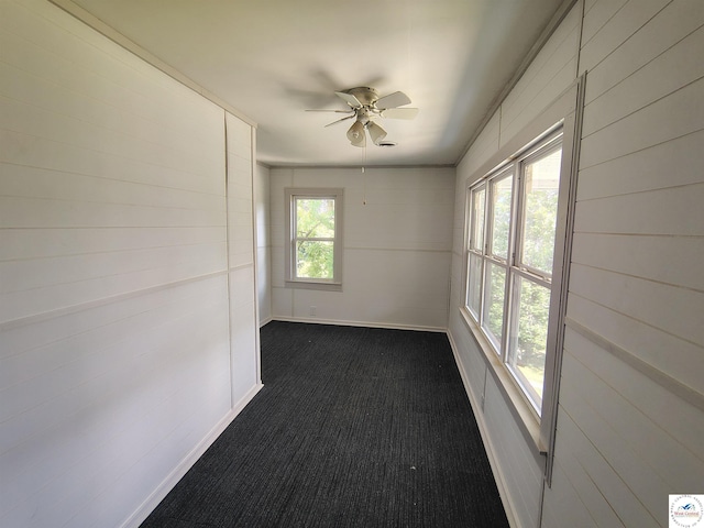 1105 Lay Ave, Warsaw, MO 65355 - empty room with dark colored carpet, a ceiling fan, and wooden walls