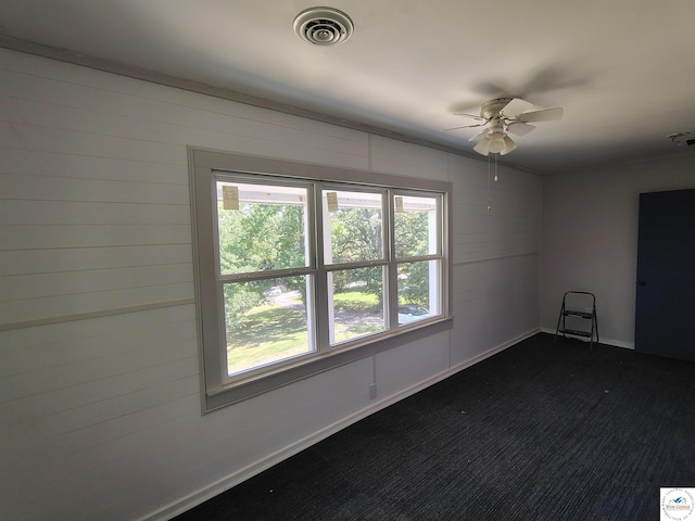 1105 Lay Ave, Warsaw, MO 65355 - spare room with ceiling fan, dark colored carpet, and wood walls