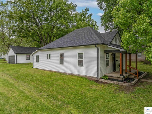 1401 S Park Ave, Sedalia, MO 65301 - view of side of property with a shingled roof, covered porch, a lawn, and an outbuilding