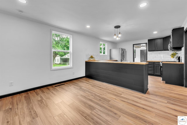 1401 S Park Ave, Sedalia, MO 65301 - kitchen with freestanding refrigerator, a peninsula, decorative backsplash, baseboards, and light wood-style floors
