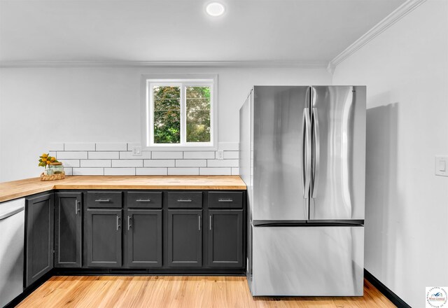 1401 S Park Ave, Sedalia, MO 65301 - kitchen with appliances with stainless steel finishes, butcher block counters, ornamental molding, tasteful backsplash, and light wood-type flooring