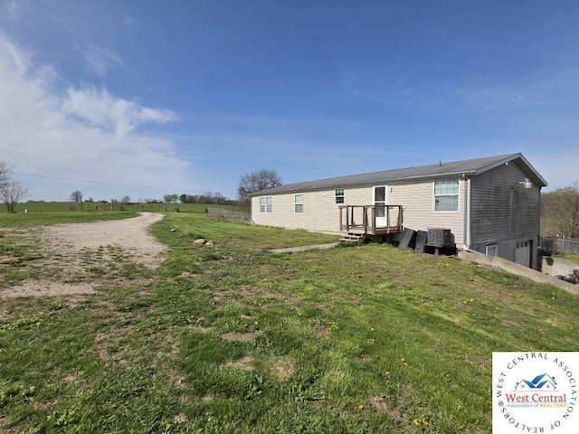 rear view of house with cooling unit, a yard, and a garage