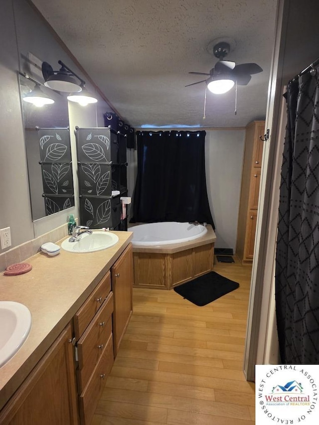 full bath with a sink, a ceiling fan, double vanity, a textured ceiling, and wood finished floors