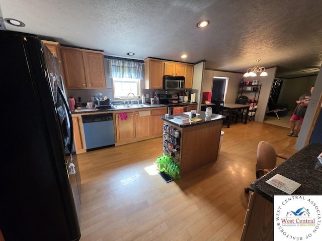 kitchen with a sink, light wood-style floors, a kitchen island, a textured ceiling, and appliances with stainless steel finishes