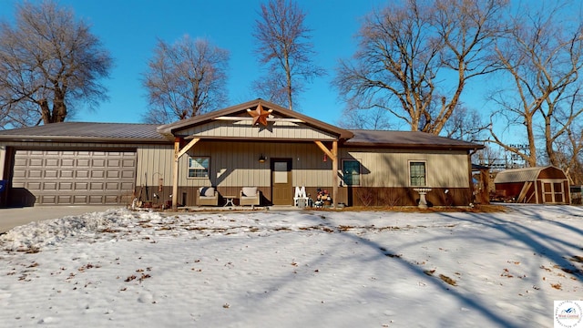 ranch-style house featuring covered porch, metal roof, a garage, driveway, and a shed
