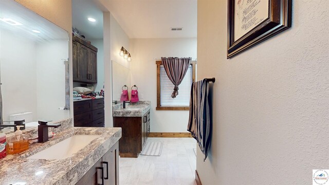 100 E Clay St, Smithton, MO 65350 - bathroom featuring two vanities, visible vents, baseboards, and a sink