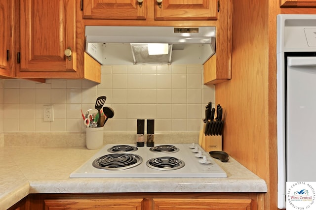 904 Leone Ave, Sedalia, MO 65301 - kitchen featuring brown cabinetry, white appliances, tasteful backsplash, under cabinet range hood, and light countertops