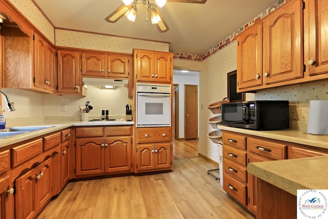 904 Leone Ave, Sedalia, MO 65301 - kitchen featuring a sink, brown cabinetry, white appliances, and wallpapered walls