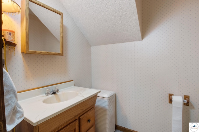28174 Apex Ave, Warsaw, MO 65355 - bathroom with vanity, a textured ceiling, vaulted ceiling, and wallpapered walls