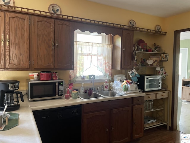 kitchen featuring light countertops, a sink, dark wood-type flooring, stainless steel microwave, and dishwasher