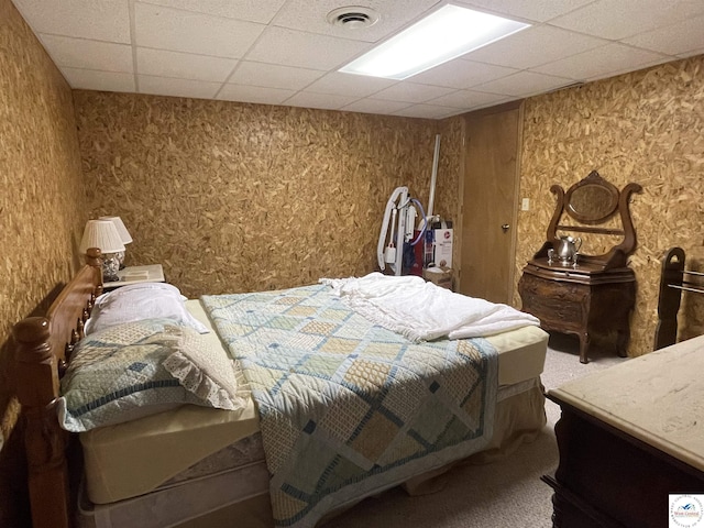 bedroom with a paneled ceiling, visible vents, and carpet floors