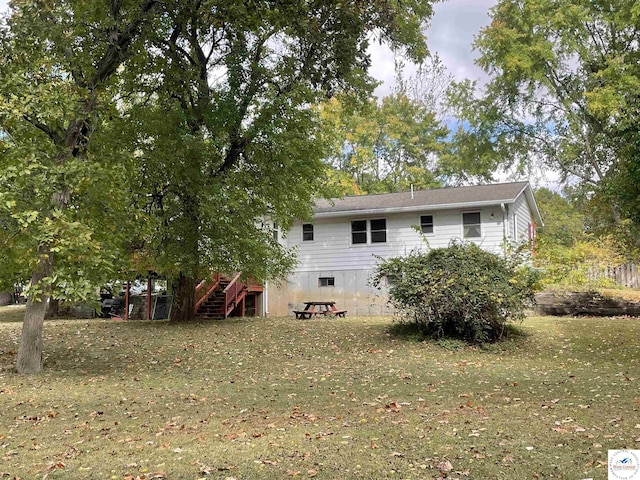 back of house with a lawn and stairway