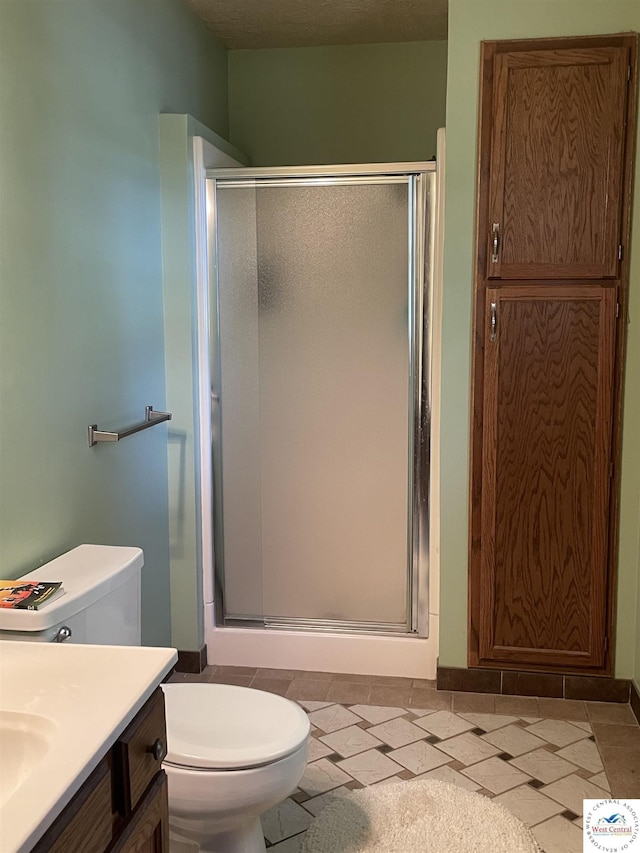 bathroom with a stall shower, vanity, and toilet