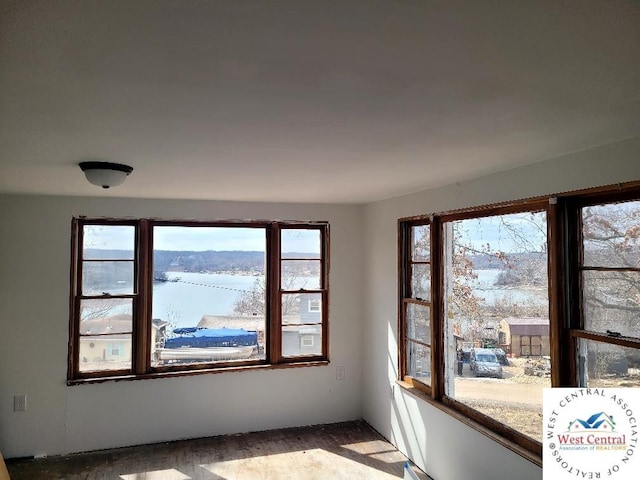 unfurnished room with a water view and wood finished floors