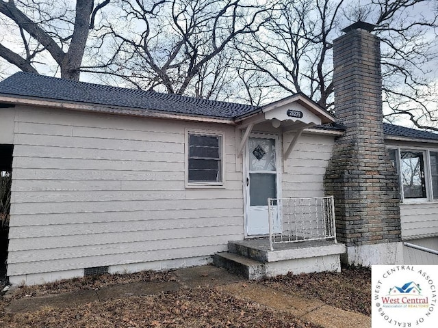 ranch-style home with a chimney, crawl space, and roof with shingles