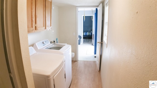 252 Shawn Ave, Lincoln, MO 65338 - laundry room with washing machine and clothes dryer, cabinet space, light wood-style flooring, and a textured wall