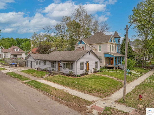 victorian house with roof with shingles, a residential view, a front lawn, a garage, and concrete driveway
